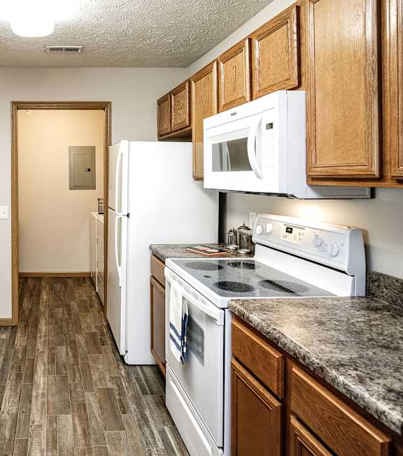 A kitchen with wooden cabinets and a white dishwasher. at Standing Bear Lake, Nebraska