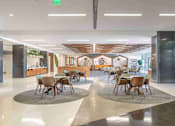 Thumbnail 9 of 24 - A modern dining area with two round tables surrounded by chairs.