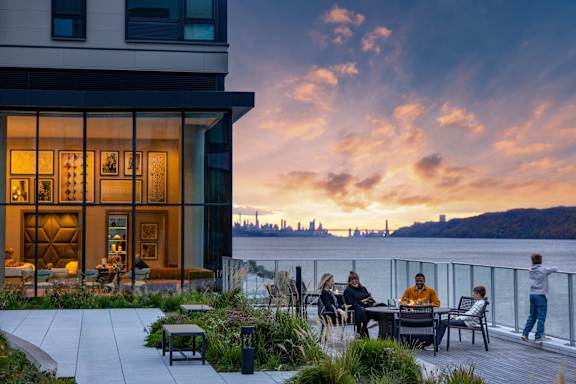 A group of people are sitting on a patio overlooking a body of water.