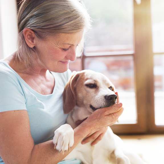 A woman is holding a dog in her arms.