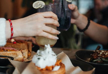a couple of people holding drinks at a table with food