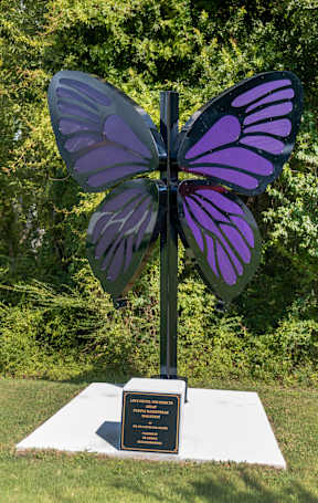 A purple butterfly sculpture is mounted on a black pole.