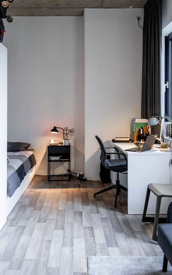 A room with a bed, desk, and chair.