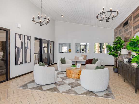 A modern living room with a white sofa set, a wooden coffee table, and a large rug.