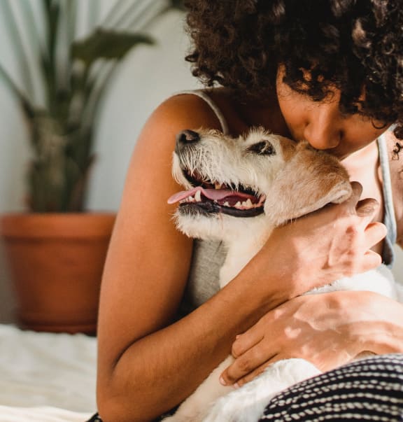 a woman hugging her dog on a bed