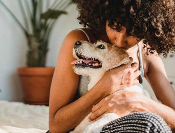 a woman hugging her dog on a bed