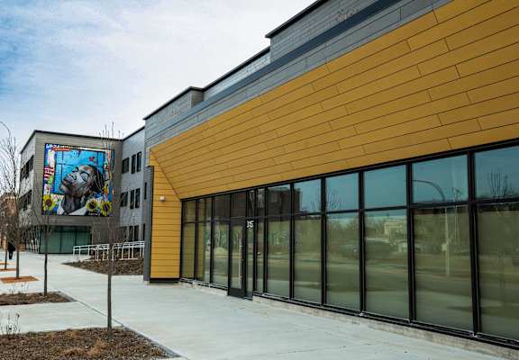 A building with a yellow and grey exterior and a mural on the side.