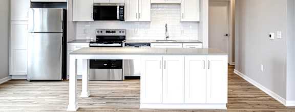 A modern kitchen with white cabinets and a wooden floor.