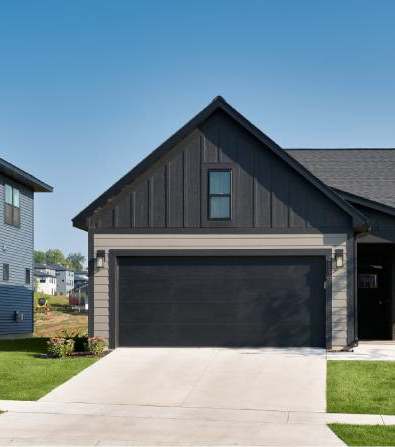 A modern house with a garage door and a tree in front.
