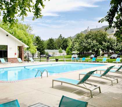 A pool with sun loungers and a building in the background. at The Pointe, LaVista, NE