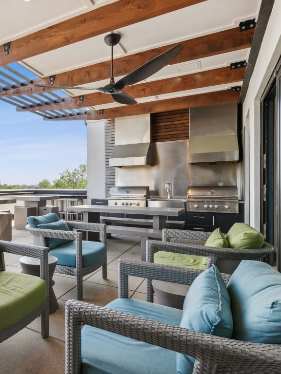 a rooftop patio with wicker chairs and tables and a kitchen