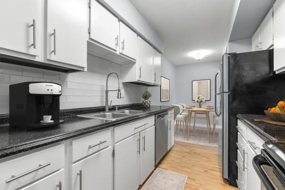 a kitchen with white cabinets and a sink and a refrigerator at West Pointe Apartments in Burlington, NC