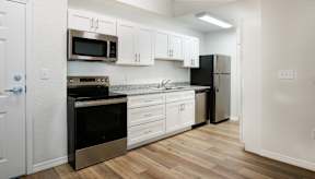 A kitchen with white cabinets and a black fridge.
