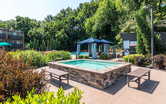 a large pool with lounge chairs and umbrellas in front of a building at The Falls, Kansas, 66202