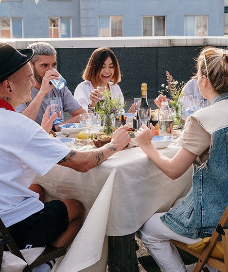 a group of people sitting around a table eating and drinking wine