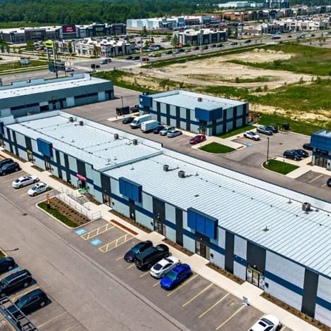 A parking lot with several cars parked in front of a large industrial building.
