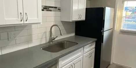A kitchen with white cabinets and a black refrigerator.