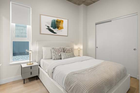 A bedroom with a large bed and a painting above it.