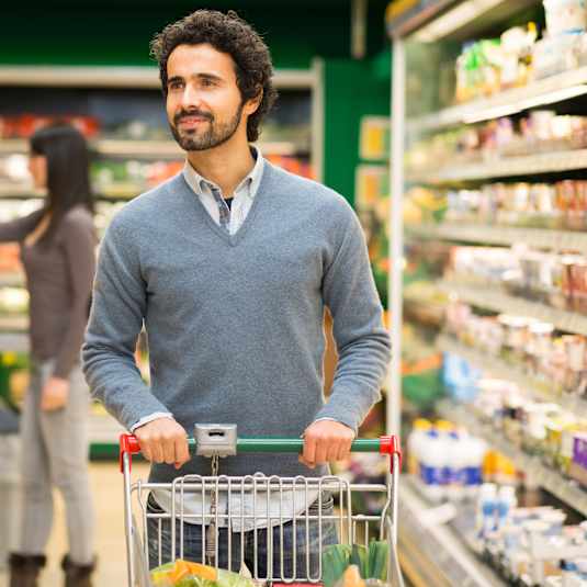 A man with a shopping cart in a grocery store.