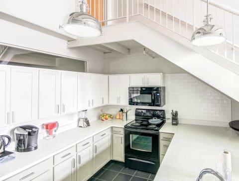 a white kitchen with black appliances and white cabinets