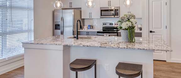A kitchen with a marble countertop and two bar stools.