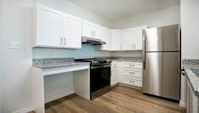 A kitchen with a stainless steel refrigerator and a granite countertop.