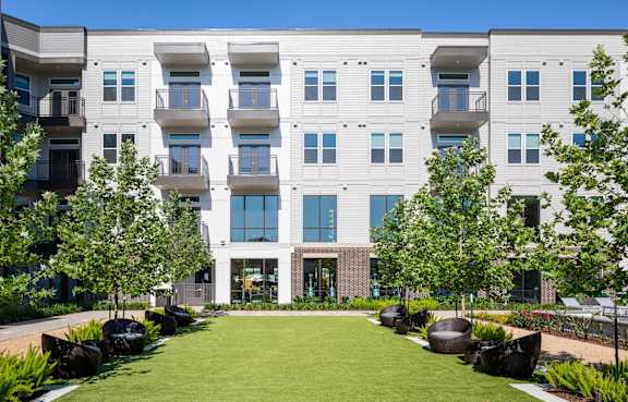 A modern apartment building with a green lawn in front.