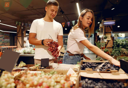 a couple buying grapes at a market
