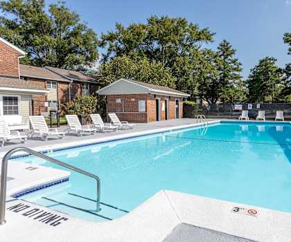 A swimming pool with a diving board and lounge chairs.