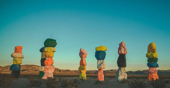 a group of totem poles in the desert against a blue sky