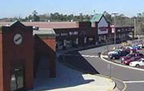 A parking lot with cars and a building with a clock on it.