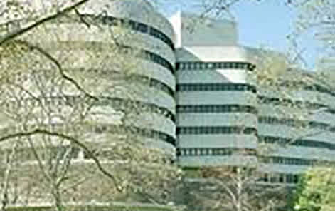A large building with a curved design is surrounded by trees.