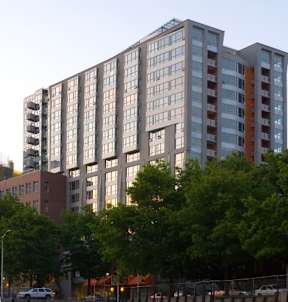 A large building with many windows is surrounded by trees.