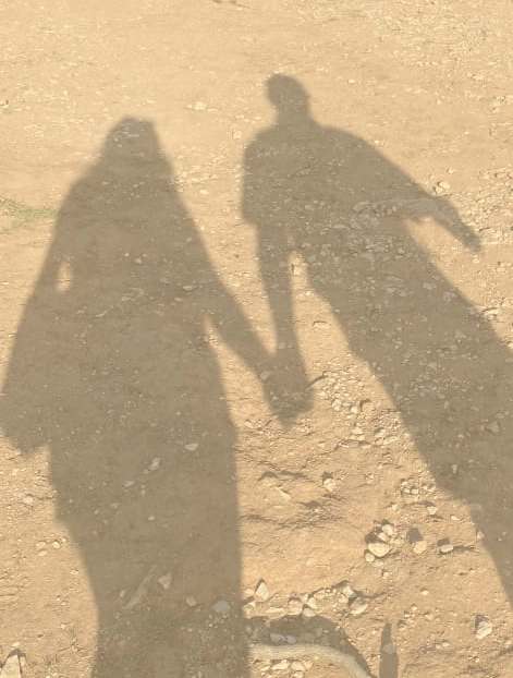 A shadow of a couple holding hands is cast on the ground.