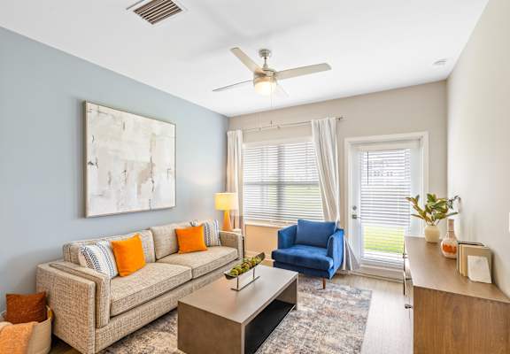 a living room with a couch and a chair and a ceiling fan