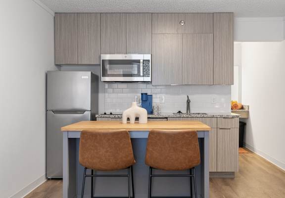a kitchen with stainless steel appliances and a island with two chairs at The Teale Navy Yard, North Charleston, South Carolina