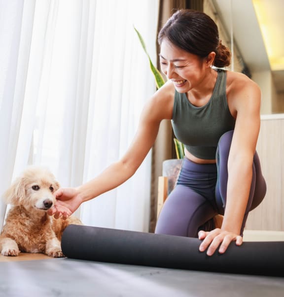 a woman in a green tank top and purple leggings is petting her dog while