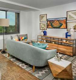 Living room with a grey couch, a round table at The Graham at Southern Towers, Alexandria, Virginia, 22311