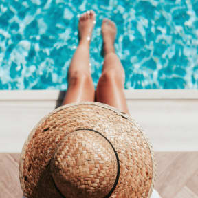 Woman Wearing Hat Sitting by Pool