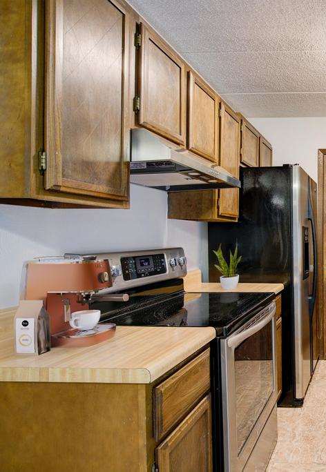 A kitchen with wooden cabinets and a black refrigerator.