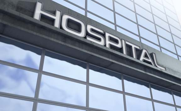 A hospital sign is mounted on a glass building.