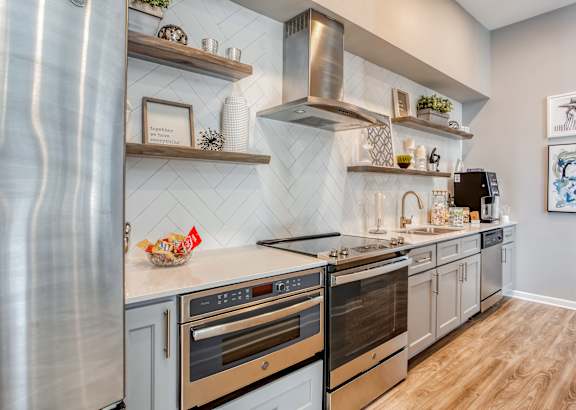 A modern kitchen with stainless steel appliances and wooden shelves.