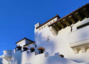 Thumbnail 2 of 30 - A white building with a red tile roof and a balcony with plants.