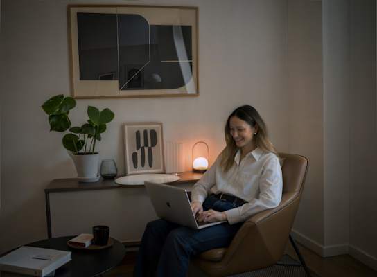 A woman is sitting in a chair using a laptop.