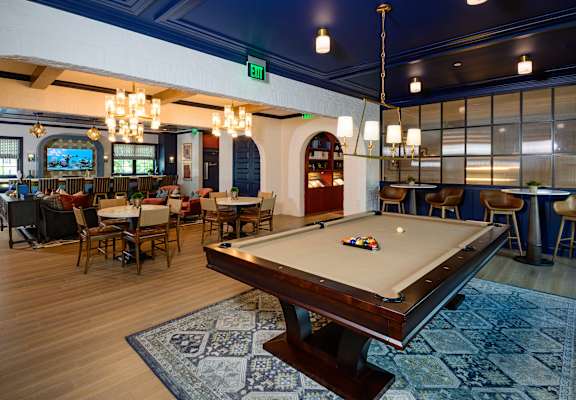 A pool table is in the middle of a room with a blue rug.
