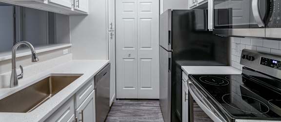 A kitchen with black appliances and white cabinets.
