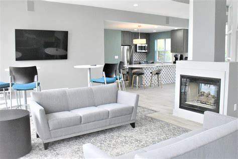 A grey couch is in the middle of a white room with a fireplace.