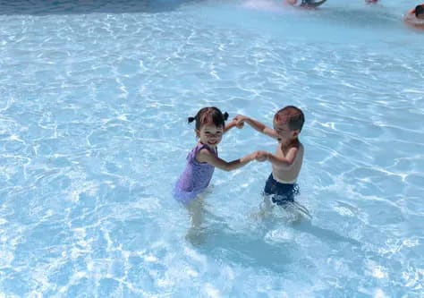 two children are playing in the water in a pool