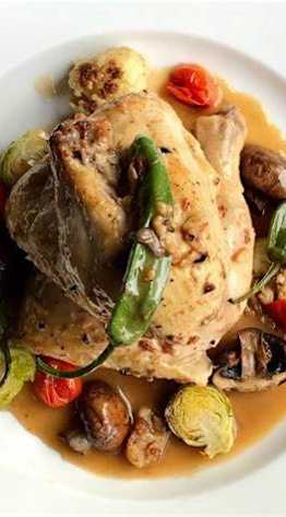 A white plate with a piece of chicken and vegetables.