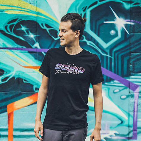 a man wearing a black shirt standing in front of a graffiti wall